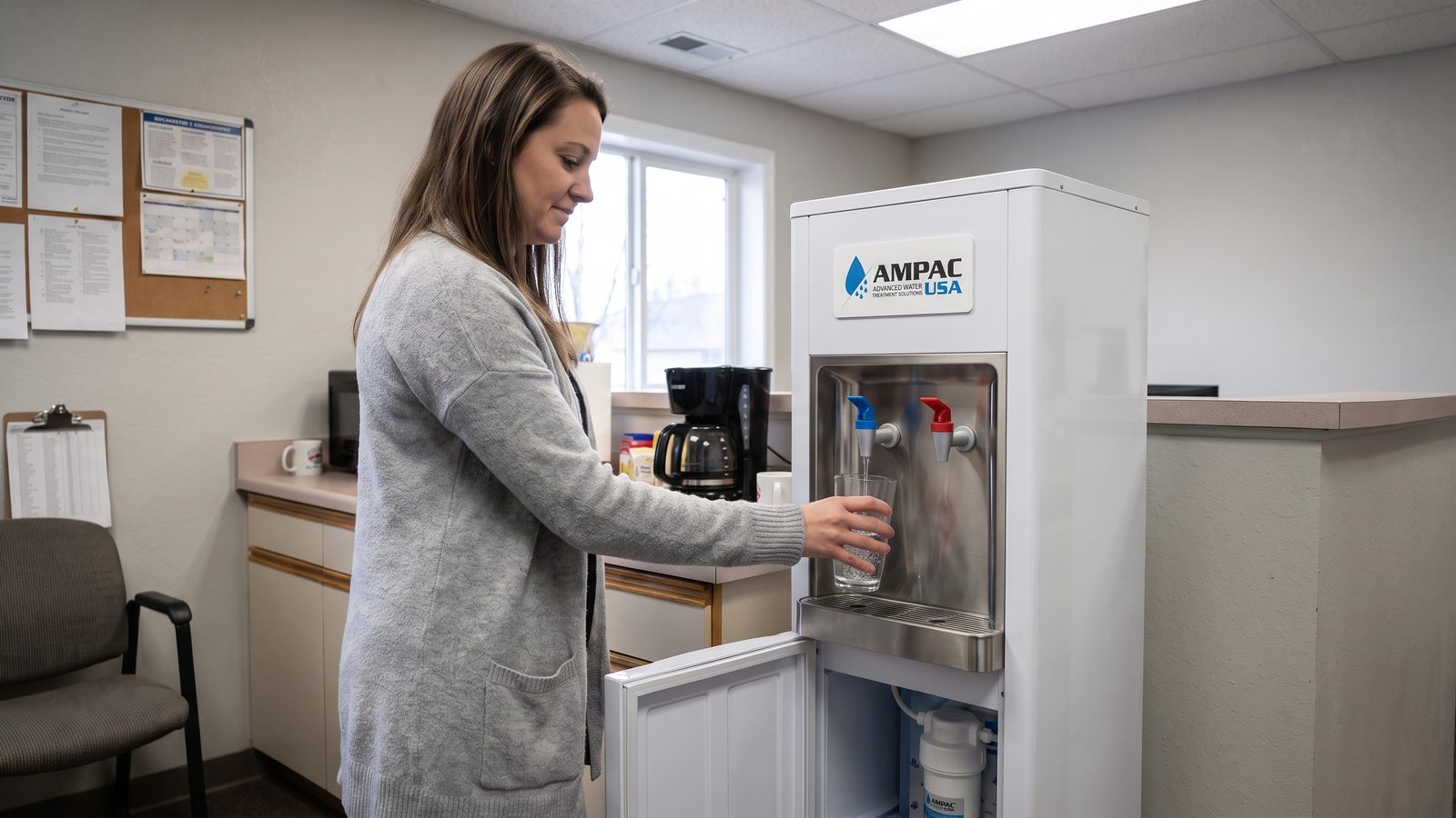 Office worker filling a glass at a bottleless AMPAC USA reverse osmosis water cooler